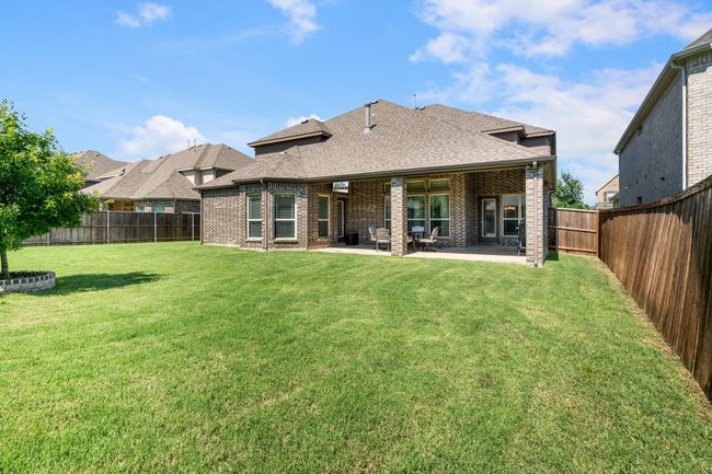 Rear view of house featuring brick siding, a shingled roof, a fenced backyard, and a patio | Image 36