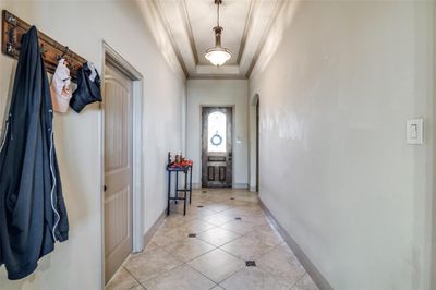 Doorway with a tray ceiling, crown molding, and light tile patterned floors | Image 3