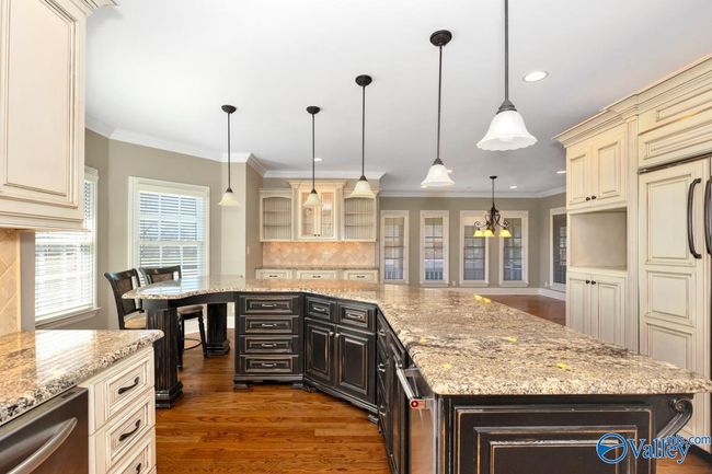 Wood flooring, wood cabinetry, kitchen island with bar seating, recessed lighting | Image 17