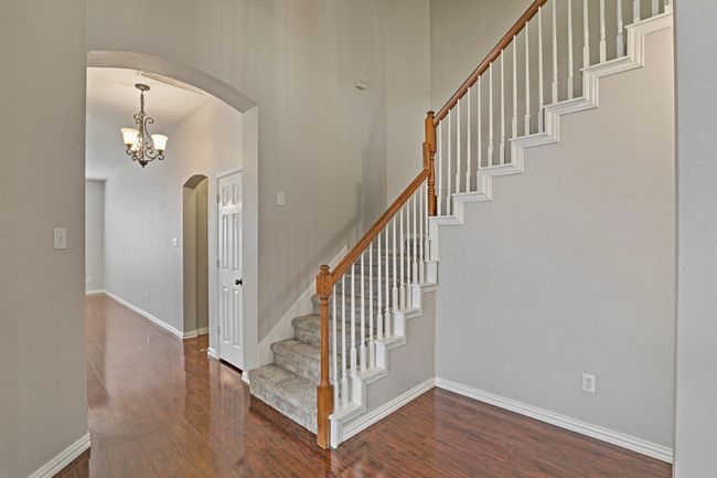 Foyer entrance with arched walkways, wood finished floors, stairway, and a chandelier | Image 5