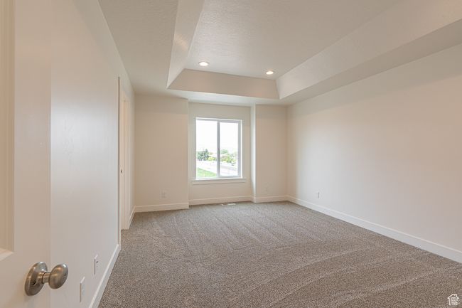 Empty room with a raised ceiling, carpet flooring, a textured ceiling, and recessed lighting | Image 17