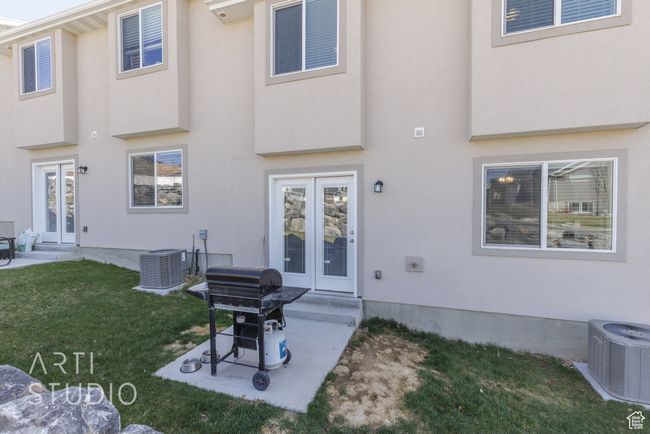 Rear view of property with stucco siding, french doors, cooling unit, a patio area, and a lawn | Image 25