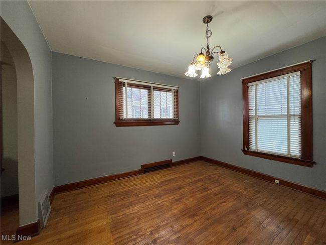 Spare room with arched walkways, wood-type flooring, visible vents, and baseboards | Image 13