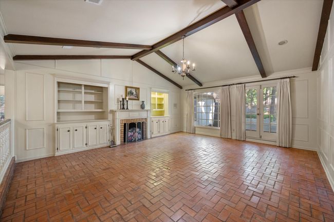 Beautiful sunken living room featuring brick floors, hand painted chandelier, and fireplace with book shelves on either side. | Image 6