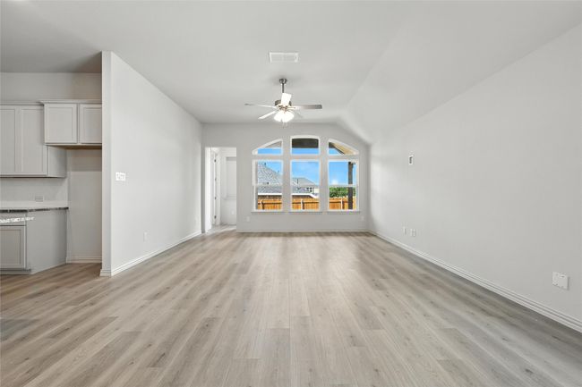 Unfurnished living room with a ceiling fan, light wood-type flooring, and vaulted ceiling | Image 9