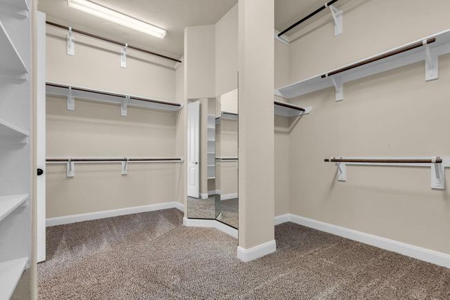 This expansive walk-in closet is a dream come true, featuring abundant hanging space, built-in shelving, and thoughtfully designed storage solutions to keep everything organized. Full-length mirrors add both functionality and style, making it easy to get ready in one beautifully appointed space. | Image 23