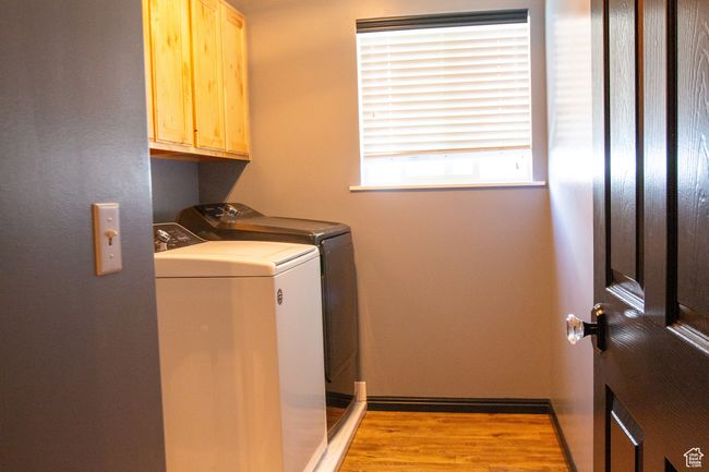 Laundry area with cabinet space, washing machine and dryer, light wood-type flooring, and baseboards | Image 20