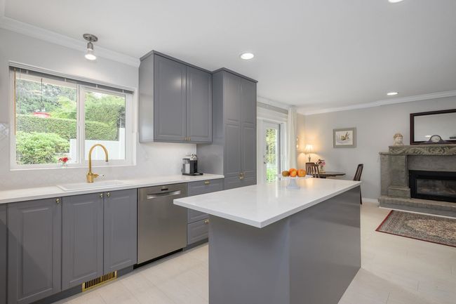 Kitchen with dishwasher, gray cabinetry, light countertops, crown molding, and backsplash | Image 12