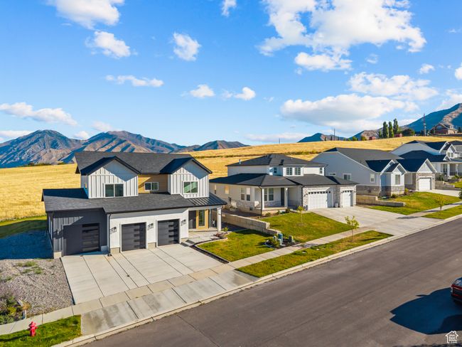 View of front facade with board and batten siding, a mountain view, concrete driveway, a garage, and a residential view | Image 8