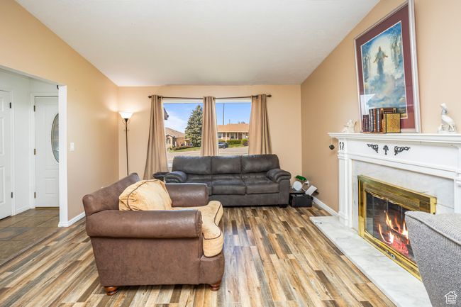 Living area with baseboards, wood finished floors, lofted ceiling, and a fireplace | Image 4