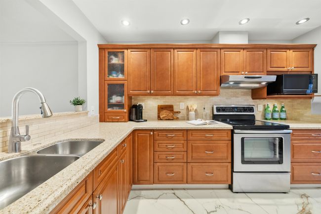 Kitchen featuring black microwave, under cabinet range hood, a sink, marble finish floor, and stainless steel electric range | Image 8