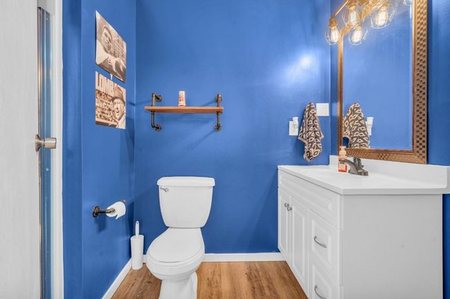 Half bathroom featuring toilet, vanity, baseboards, and wood finished floors | Image 23