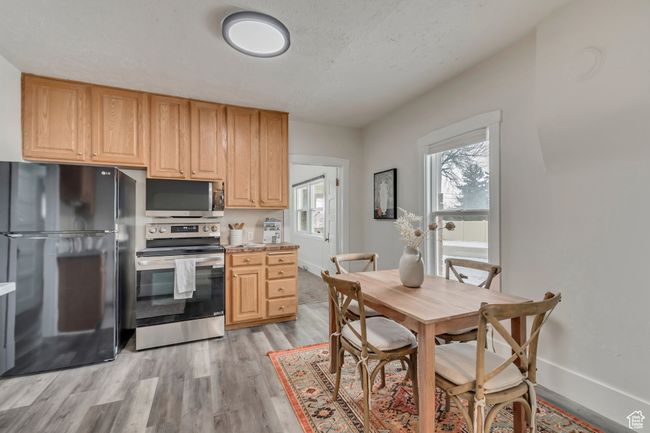 Kitchen featuring light wood-type flooring, baseboards, appliances with stainless steel finishes, and light countertops | Image 7