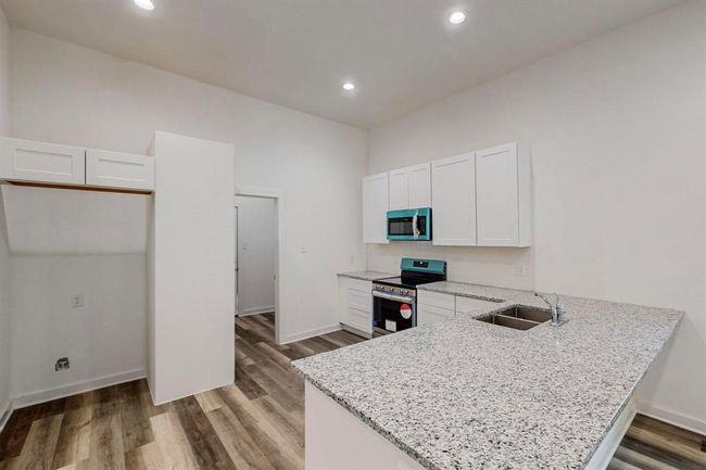 Kitchen with kitchen peninsula, stainless steel appliances, hardwood / wood-style floors, white cabinetry, and sink | Image 13