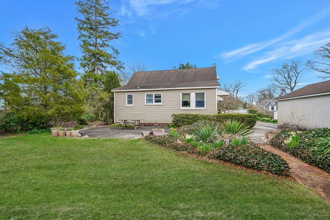 Rear view of property featuring a patio, a yard, and roof with shingles | Image 6