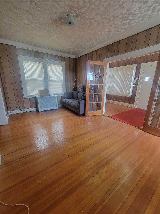 Unfurnished room with wooden walls, crown molding, hardwood / wood-style flooring, and a textured ceiling | Image 8