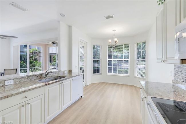 Kitchen featuring visible vents, a sink, white appliances, and ceiling fan with notable chandelier | Image 8
