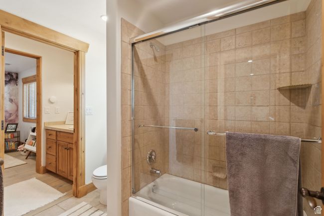 Bathroom featuring vanity, toilet, shower / bath combination with glass door, and wood finished floors | Image 34