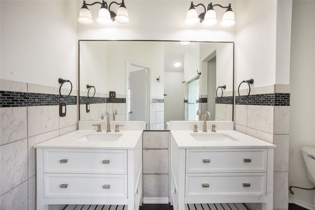 Bathroom featuring toilet, a sink, two vanities, and tile walls | Image 8