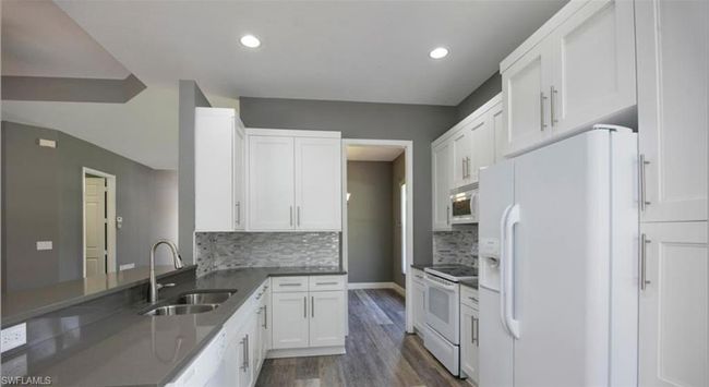 Kitchen featuring white cabinetry, sink, backsplash, dark hardwood / wood-style flooring, and white appliances | Image 5