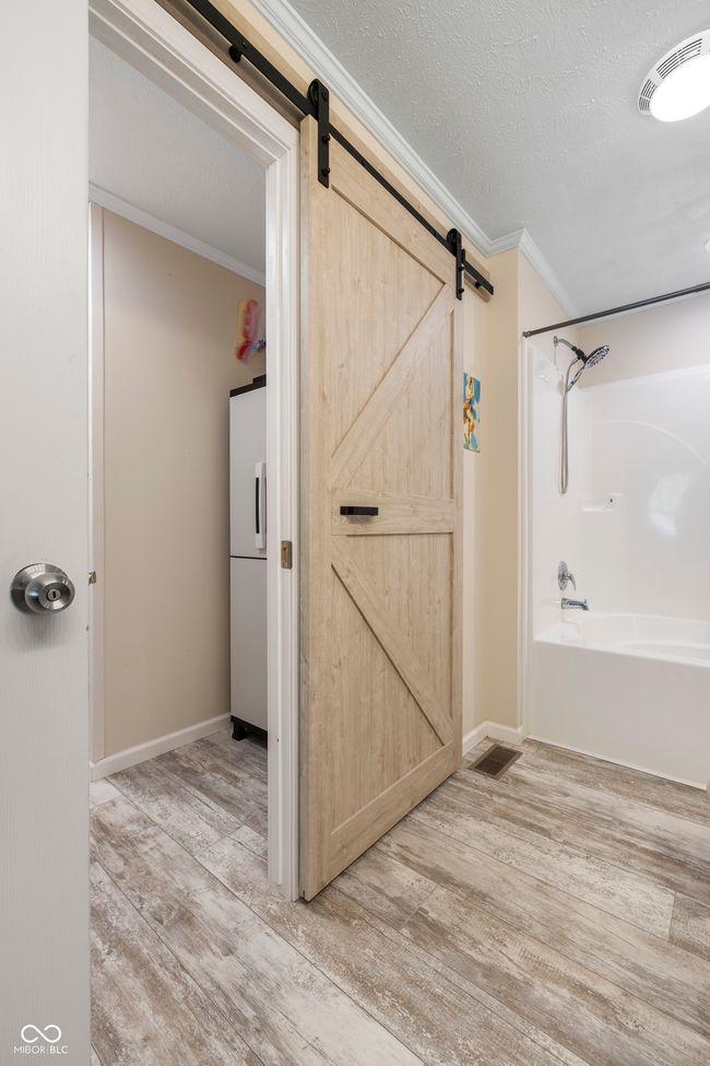 bathroom with wood finished floors, ornamental molding, tub / shower combination, baseboards, and a textured ceiling | Image 30