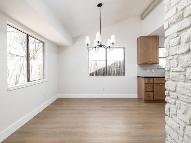Unfurnished dining area with an inviting chandelier, lofted ceiling, baseboards, and light wood finished floors | Image 12