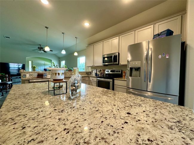 Kitchen featuring appliances with stainless steel finishes, a ceiling fan, light stone countertops, recessed lighting, and pendant lighting | Image 15