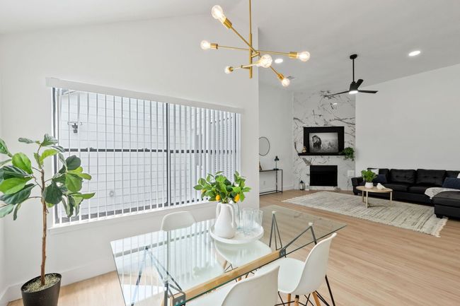 Dining room featuring lofted ceiling, a notable chandelier, and a premium fireplace | Image 12