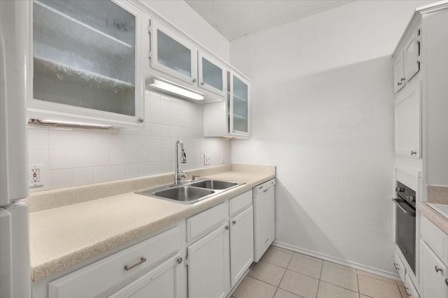 Kitchen with white dishwasher, oven, light countertops, tasteful backsplash, and light tile patterned floors | Image 20