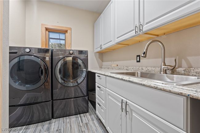 Laundry room with cabinet space, a sink, and washing machine and clothes dryer | Image 59