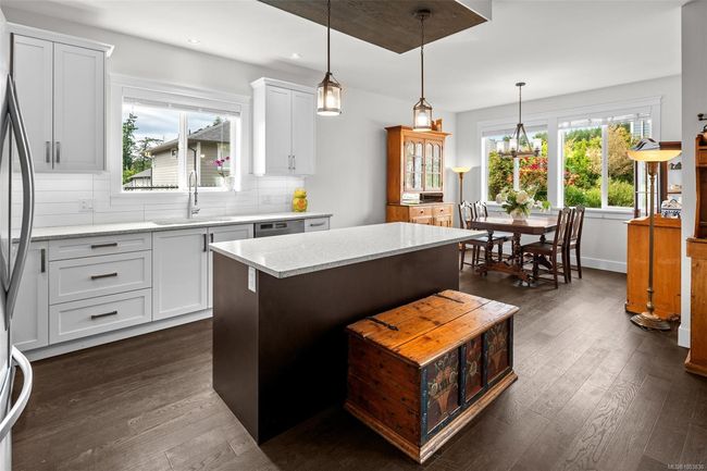 Kitchen featuring dark wood-type flooring, a center island, decorative backsplash, white cabinets, and recessed lighting | Image 17