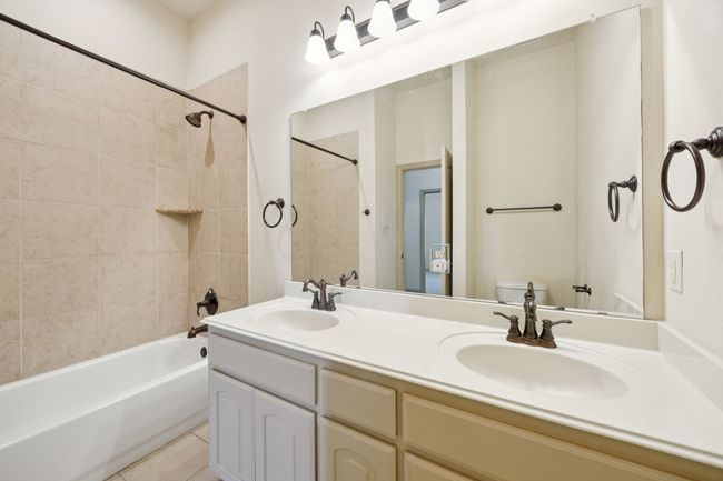 Bathroom featuring toilet, shower / tub combo with curtain, double vanity, and tile patterned flooring | Image 34