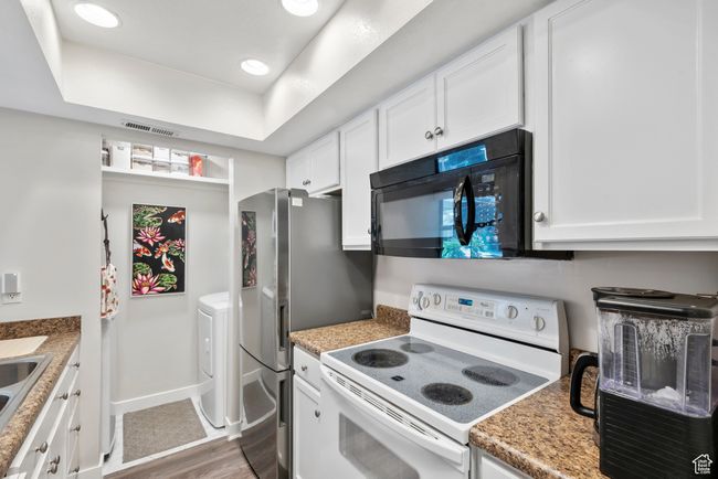 Kitchen featuring white electric stove, black microwave, wood finished floors, white cabinets, and recessed lighting | Image 14