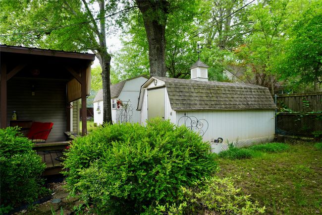 View of side of property featuring roof with shingles, a storage shed, fence, an outdoor structure, and a chimney | Image 25