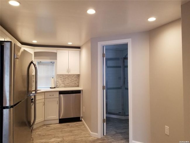 Kitchen featuring appliances with stainless steel finishes, light wood-style floors, recessed lighting, white cabinetry, and light countertops | Image 7