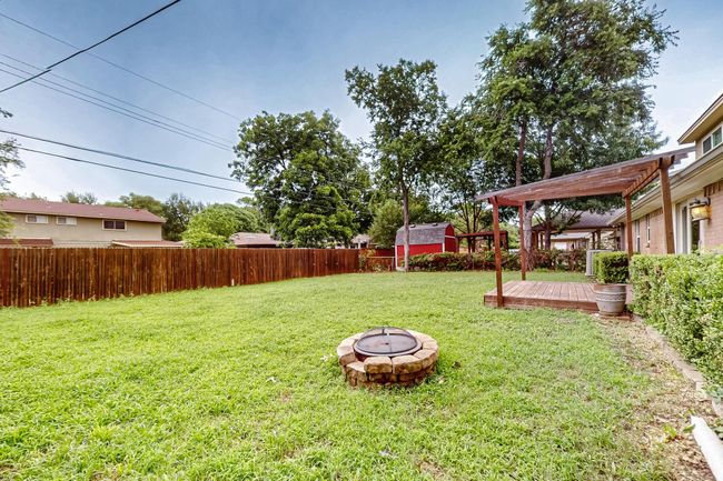 Fenced backyard with a fire pit, a wooden deck, and a storage unit | Image 36