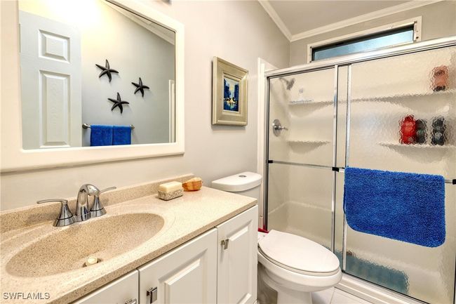 Bathroom featuring vanity, toilet, ornamental molding, and a shower with door | Image 19