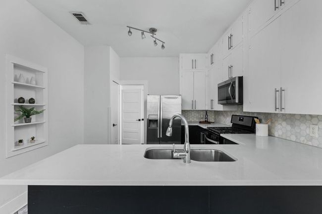 Kitchen featuring visible vents, light countertops, a sink, and appliances with stainless steel finishes | Image 11