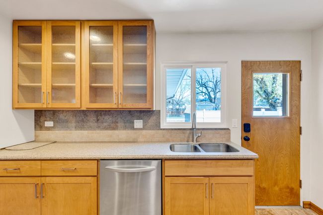 Kitchen with a sink, glass insert cabinets, tasteful backsplash, baseboards, and appliances with stainless steel finishes | Image 7