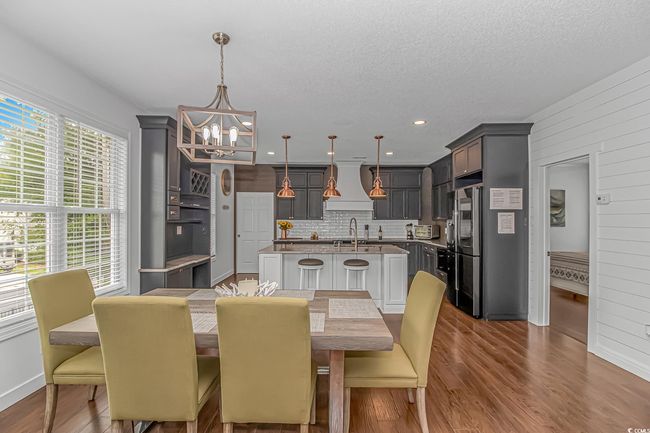 Dining space featuring a chandelier, dark wood-type flooring, baseboards, wood walls, and a textured ceiling | Image 8