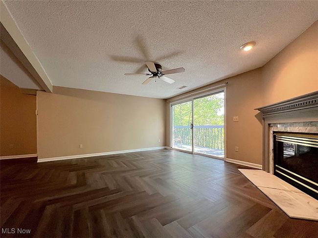 Unfurnished living room featuring a ceiling fan, a high end fireplace, and a textured ceiling | Image 4