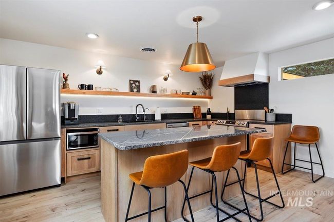 Kitchen with stainless steel appliances, open shelves, custom exhaust hood, a kitchen breakfast bar, and recessed lighting | Image 33