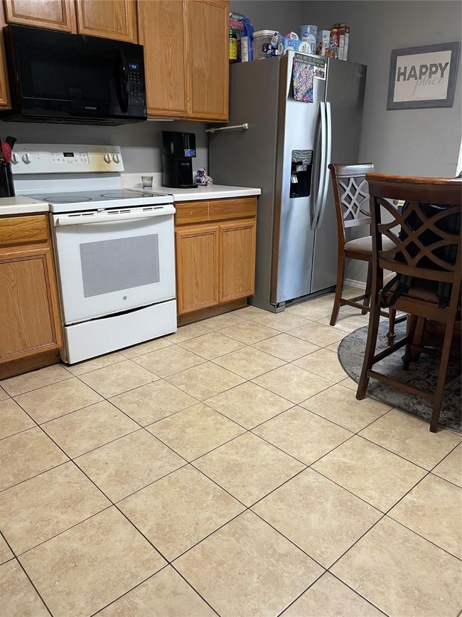 Kitchen with stove, light countertops, and brown cabinets | Image 8