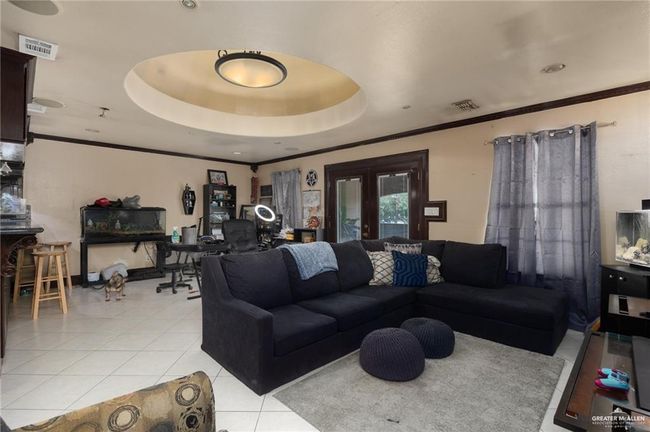 Tiled living room featuring a tray ceiling and french doors | Image 13