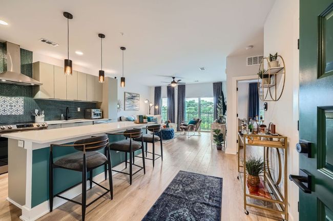 Kitchen featuring wall chimney range hood, stainless steel range, light countertops, light wood-style floors, and tasteful backsplash | Image 16