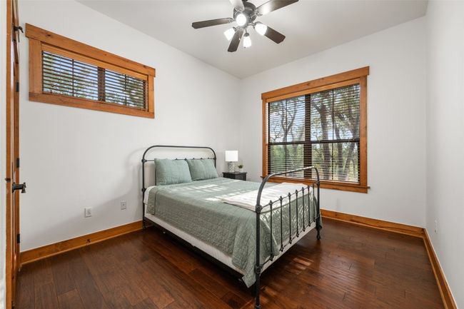 This serene secondary bedroom, on the other side of the home from the primary bedroom, features large windows that bring in natural light and offer views of the backyard. | Image 16