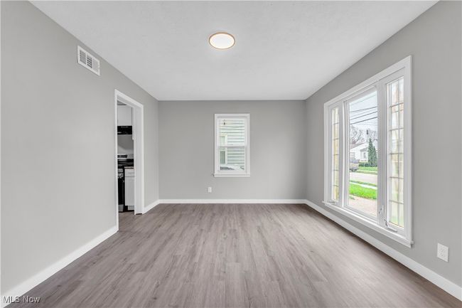 Spare room featuring baseboards, visible vents, wood finished floors, and a wealth of natural light | Image 6