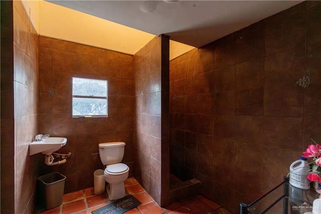 Bathroom with toilet, tile patterned floors, and tile walls | Image 31