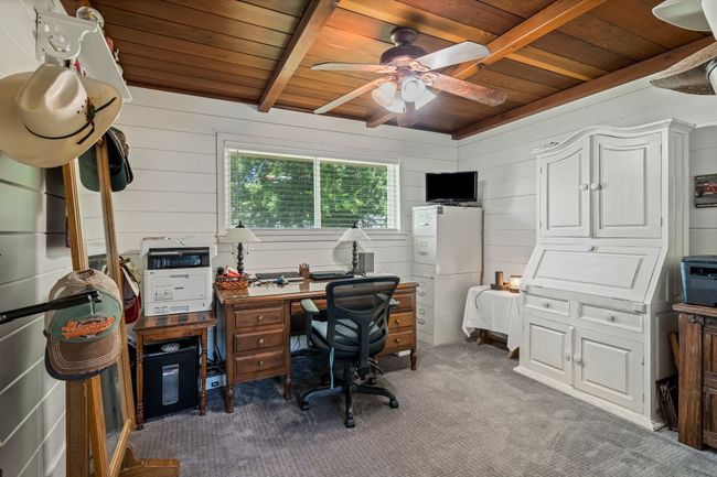 Office space featuring a wooden ceiling with exposed beams, ceiling fan, carpet floors, and wood walls | Image 22