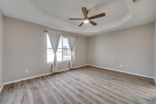 Primary Bedroom with a tray ceiling, baseboards, wood finished floors, and ceiling fan | Image 15
